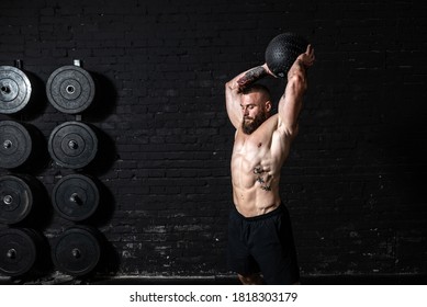 Young sweaty strong muscular fit man with big muscles doing ball throwing on the floor as hardcore cross workout training in the gym real people exercise