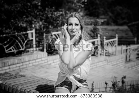 Similar – Young blonde woman portrait laughing outdoors sitting in a garden, and looking at camera.