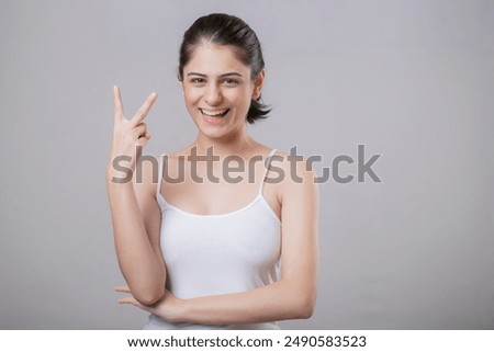 Young sweet model posing in front of camera showing victory sign
