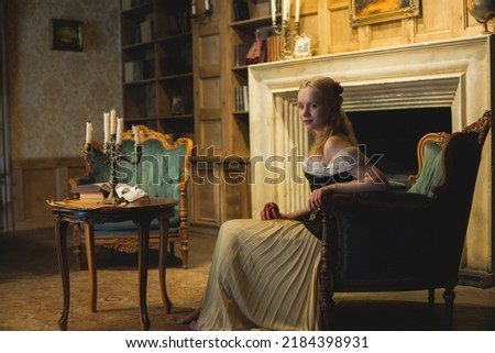 Young sweet retro style woman actress sitting on armchair in vintage interior