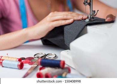 Young tailor sews a pair of trousers, horizontal