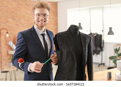 Young tailor working with mannequin in atelier