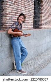 Young Taiwanese Man Smiling And Playing Acoustic Ukulele Guitar At Street.