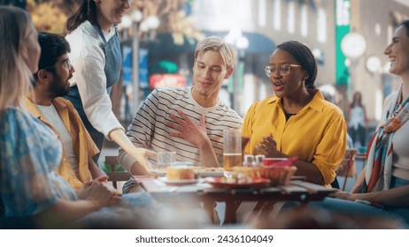 Young Talented Colleagues Enjoying a Work Break in a Cafe. Waiter Bringing a Delicious Italian Pizza. Young Men and Women Having Fun Conversations on a Terrace, Enjoying Tasty Food and Beverages - Powered by Shutterstock