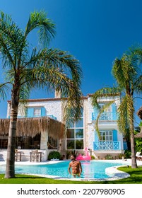 A Young Tanning Man At A Swimmingpool With Red Pink Flamingo, Pink Flaming By The Pool. 