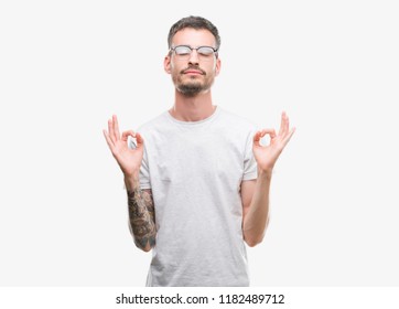 Young tattooed adult man relax and smiling with eyes closed doing meditation gesture with fingers. Yoga concept.