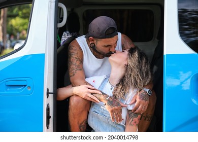 Young Tattooed Couple Kiss And Hug Sitting In The Side Of The Van.