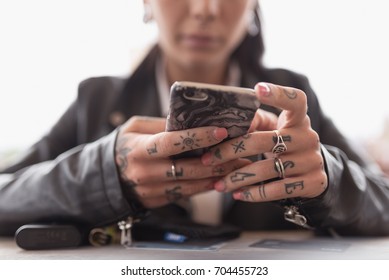 Young tattooed woman hands close up using smartphone.