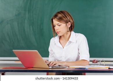 Young teacher browsing the internet through laptop inside the classroom