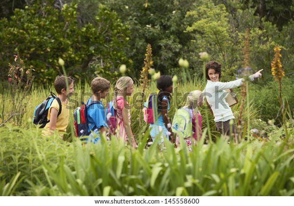 Young teacher\
with children on nature field\
trip