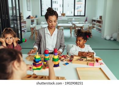 A young teacher with children playing with toys at kindergarten