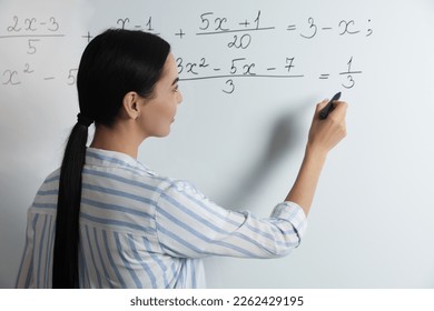 Young teacher explaining mathematics at whiteboard in classroom - Powered by Shutterstock