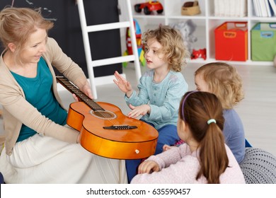 Young Teacher Having Music Lesson With Small Kids In Kindergarten