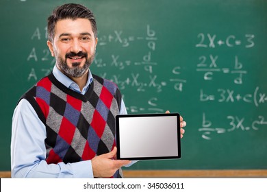 Young Teacher Holding Tablet In Classroom.