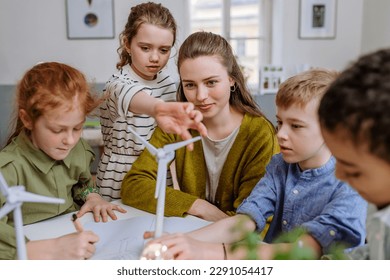 Young teacher with model of wind turbine learning pupils about wind energy. - Powered by Shutterstock