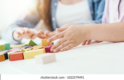 Young teacher and preschool girl playing together with colorful wood blocks, education and fun concept