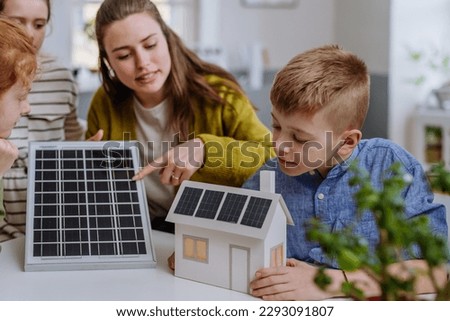 Young teacher with solar panel learning pupils about solar energy.