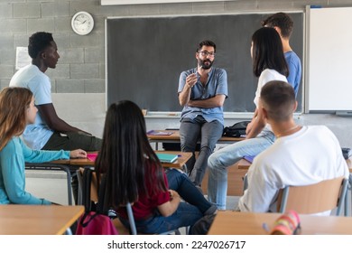 Young teacher talking with teenager students sitting at school classroom - Powered by Shutterstock