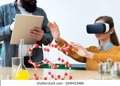 Young teacher using Virtual Reality Glasses and 3D presentation to teach students in chemistry class. Education, VR, Tutoring, New Technologies and Teaching Methods concept.  - Powered by Shutterstock