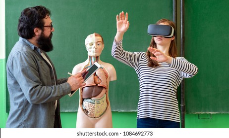 Young teacher using Virtual Reality Glasses and 3D presentation to teach students in biology class. Education, VR, Tutoring, New Technologies and Teaching Methods concept. 
