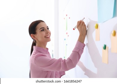 Young Teacher Writing On Whiteboard In Classroom