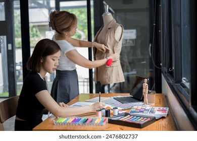 Young team asian designer women working at studio. Dressmaker makes clothes job - Powered by Shutterstock