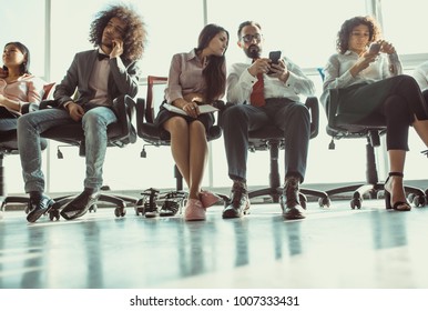 Young Team Of Coworkers Sitting On Chairs. Everybody Is Busy With Own Thoughts.