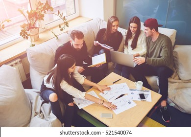 Young team of freelancers searching information making business tasks consulting with expert. Students preparing presentation using technology modern laptop wireless internet connection in coworking