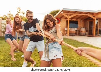 Young team having fun competing in tug of war game while on team building trip; group of friends having fun while participating in rope pulling competition - Powered by Shutterstock