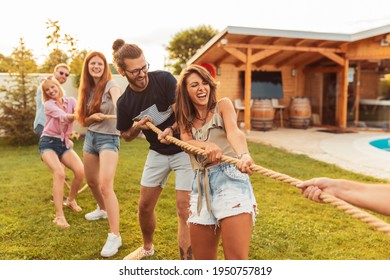 Young team having fun competing in tug of war game while on team building trip; group of friends having fun while participating in rope pulling competition - Powered by Shutterstock