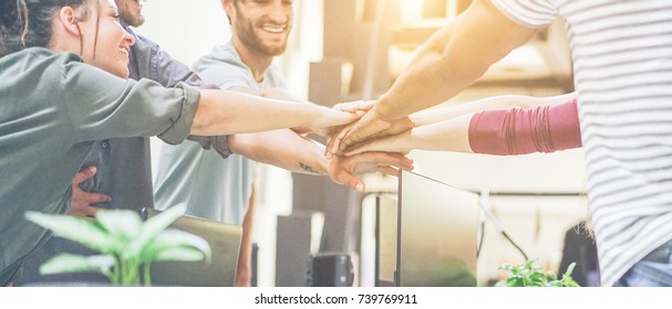 Young team putting hands up for new startup in creative office - Cheerful people giving strength motivation - Soft focus on woman with red pullover hand - Co-working and teamwork concept - Shutterstock ID 739769911