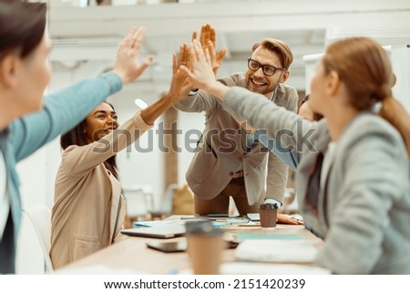 Young team putting hands up for new startup in the office