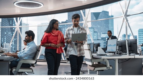 Young Team of South Asian Specialists Working on Desktop Computers at a Modern Workplace. Indian Software Developer Discussing a Financial Software Project with a Female Team Leader - Powered by Shutterstock