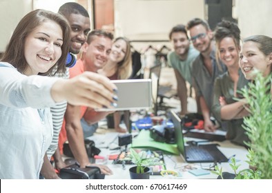 Young teamwork taking selfie in creative office - Blog co-workers having fun with rends technologies - Team,unity,loyalty,youth,trends and friendship concept - Focus on woman face with mobile phone - Powered by Shutterstock