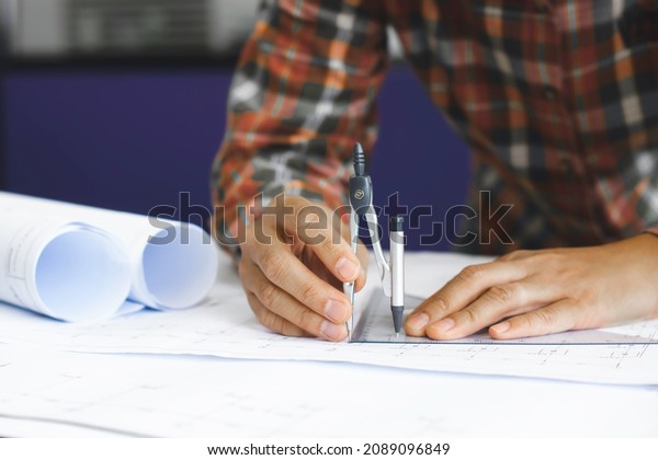 Young technician, engineer, designer holding a\
divider to work on his desk to create a project in the office.\
And\
free space to enter your\
text.