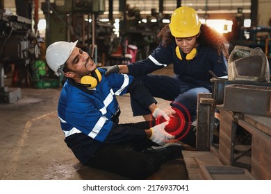 Young technician engineer or worker man in protective uniform had a leg accident lying on the floor in metal lathe factory. Safety colleague team helping him from accident. First aid training concept