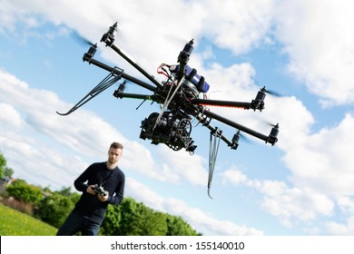 Young technician flying UAV drone with remote control in park