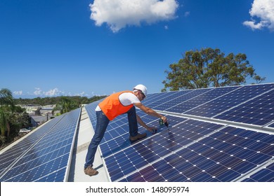 Young technician installing solar panels on factory roof - Shutterstock ID 148095974