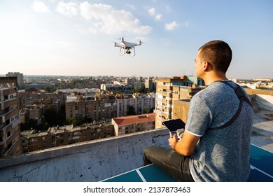 Young Technician Man Flying UAV Drone With Remote Control In City