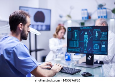 Young technician typing data for human body neurology system in science laboratory. Specialist working.