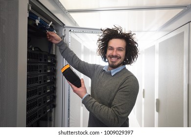 young IT technician using digital cable analyzer on server in large data center