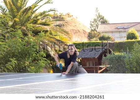 Young technician woman engineer working on a photovoltaic panels installation with a screwer