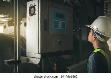 Young technicians for the refrigeration system, screw type, stand-up work, note the screen, the control panel between machines working in industrial plants.

