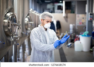 Young Technologist Putting On Protective Rubber Gloves In Production Factory. Workplace Safety.