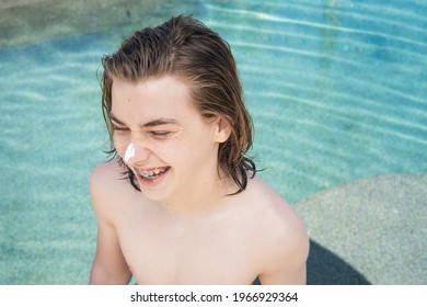 Young Teen Boy With Braces Laughing In Pool With Sun Block On His Nose