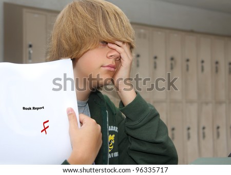 young teen boy with expression of despair upon finding a F grade on his paper.