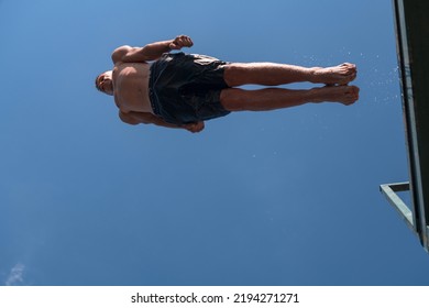 Young Teen Boy Jumping Flying And Diving In The River. Clear Blue Sky And Trees In Distance As A Natural Background.