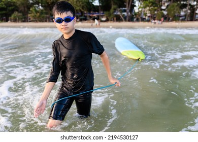 Young Teen Boy Surfer Holding Rope Of Soft Board, Bring It To Try Again In Wave. Rookie Teenager Surfboard Student Playing On Water In Strive Focus Action. Sports Teenagers Practice Surfing Lessons.