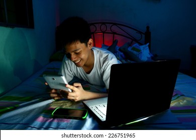 Young Teen in front of a laptop computer and on a bed and using a tablet Photo of a Young Teen in front of a laptop computer and on a bed and using a tablet - Powered by Shutterstock