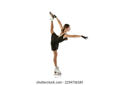 Young teen girl, junior female figure skater in black stage costume skating isolated over white background. Concept of skills, sport, beauty, winter sports. Copy space for ad